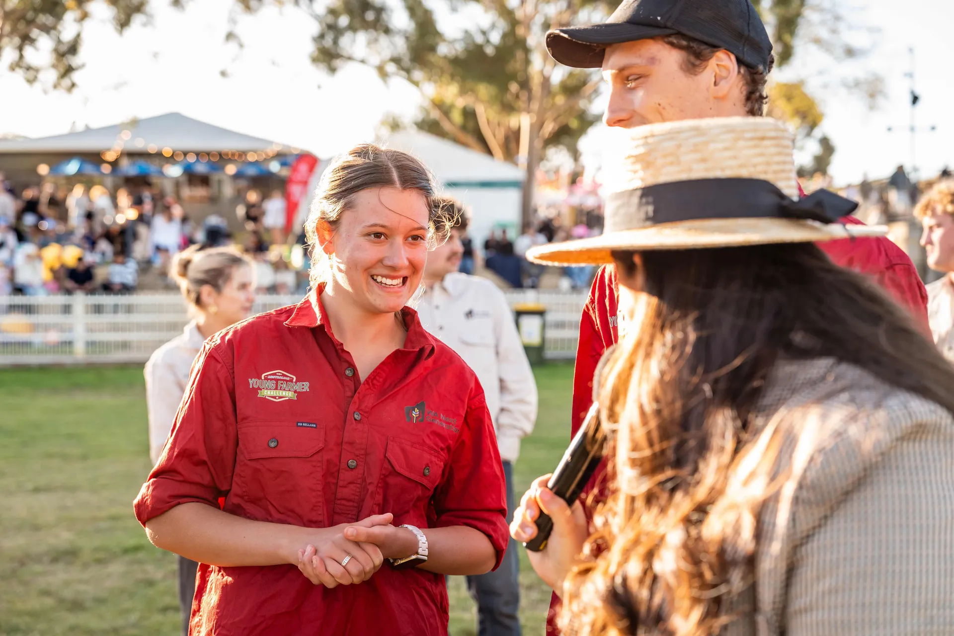Young farmer speaking with others at an outdoor agricultural event