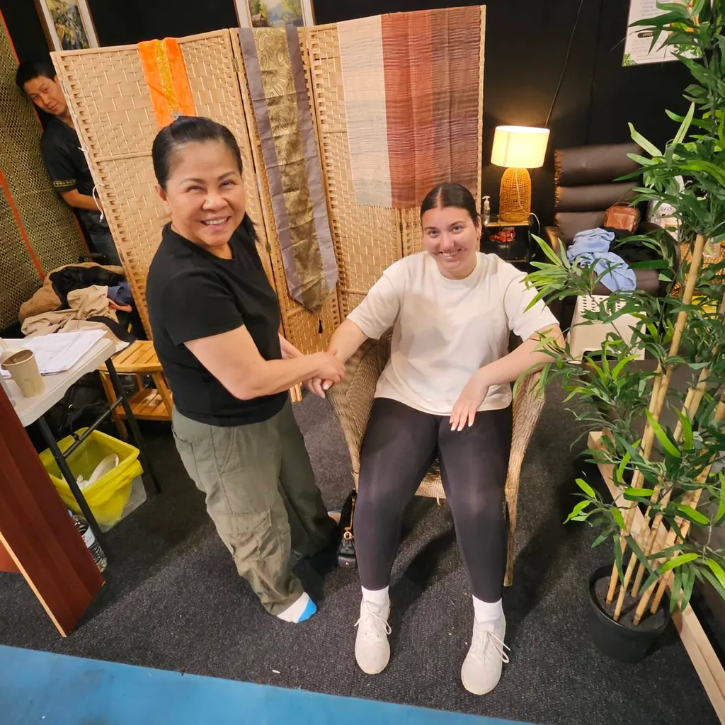 Masseuse and customer smiling while giving a hand massage 