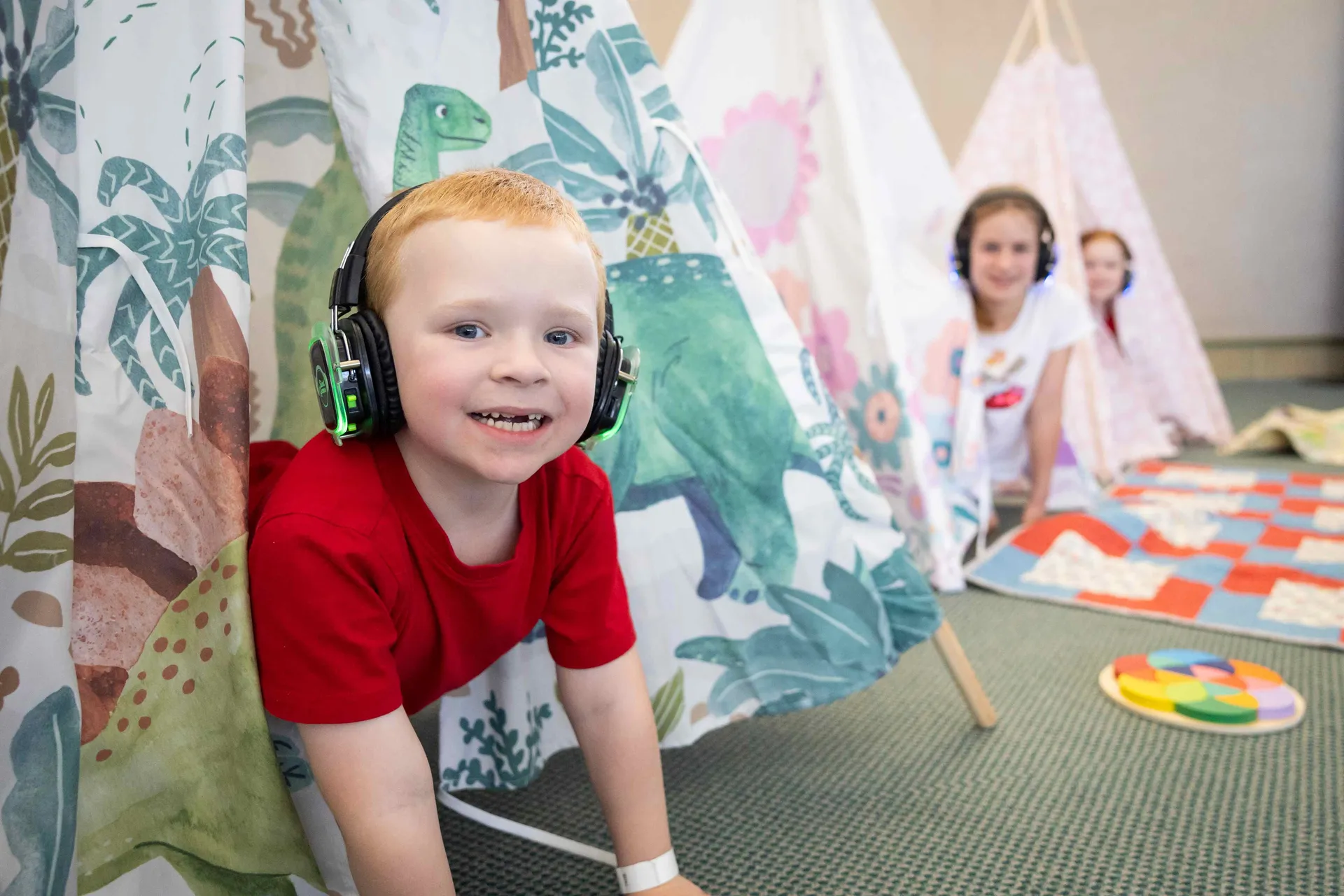 Children wearing headphones playing inside small teepees in the sensory space at the Perth Royal Show.