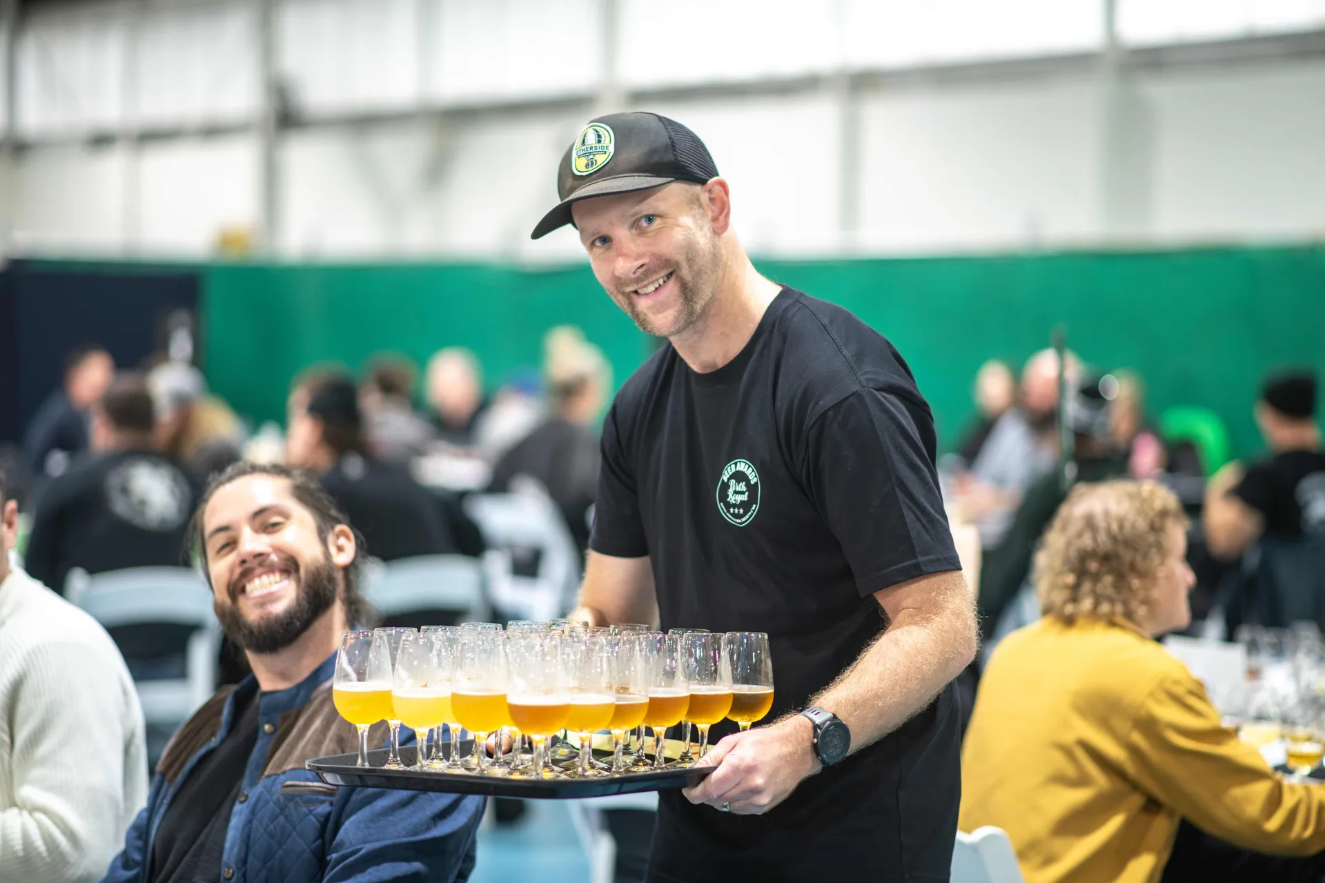 Staff member carrying a tray of beer samples to judges during tasting at the Perth Royal Food Awards.