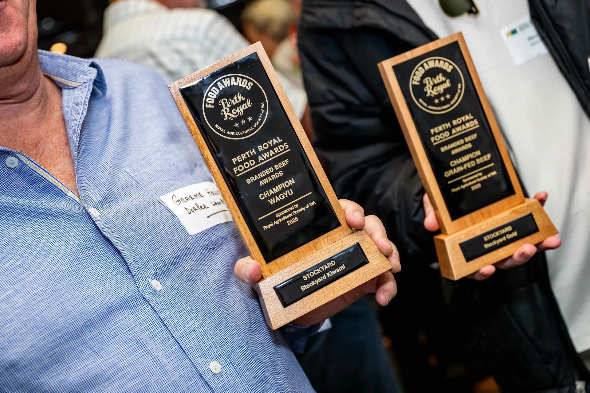 Two people holding Perth Royal Food Awards trophies for branded beef, recognising champion Wagyu and grain-fed beef products.
