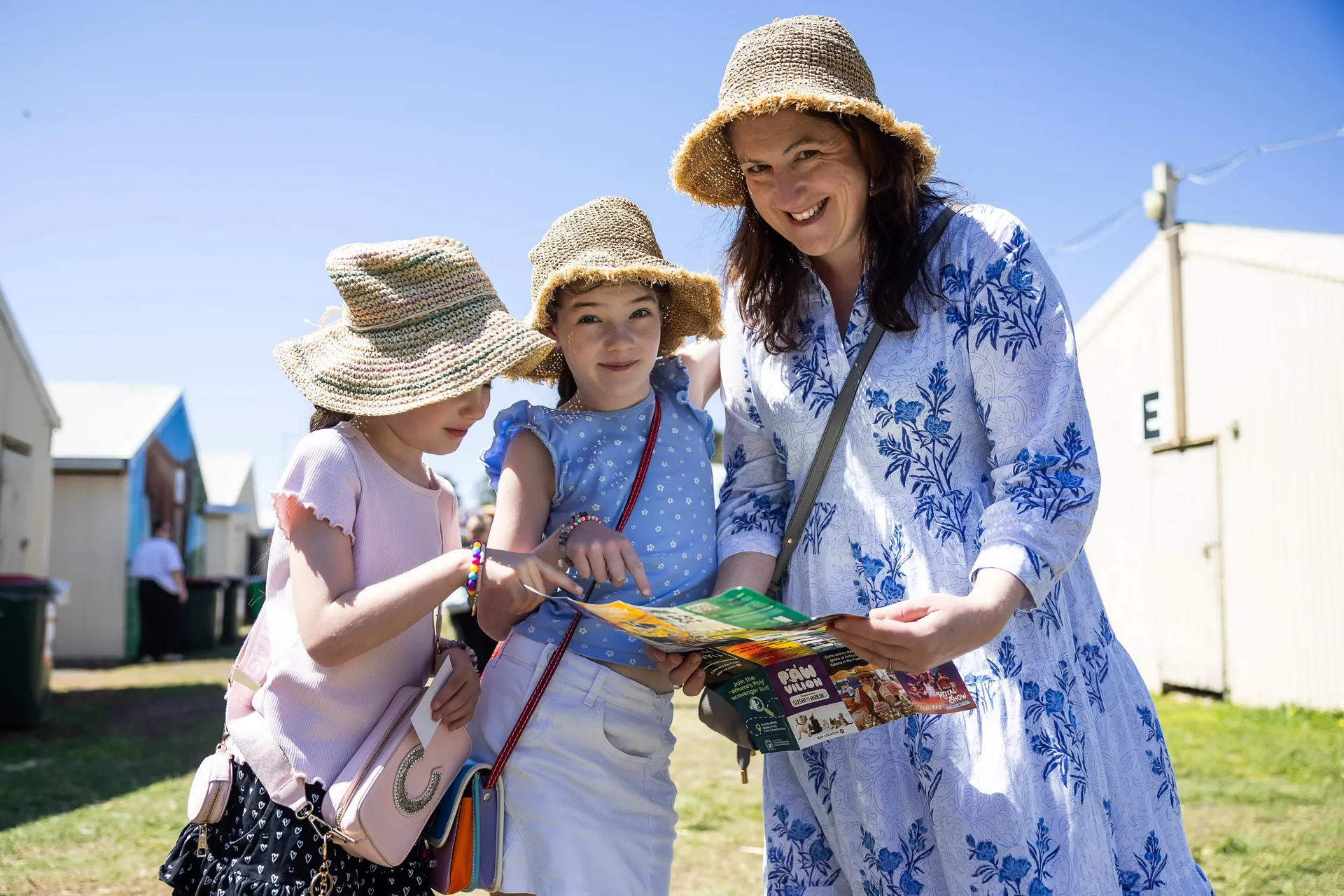 Family with two children wearing sun hats looking at a show map together at the Perth Royal Show on a sunny day.