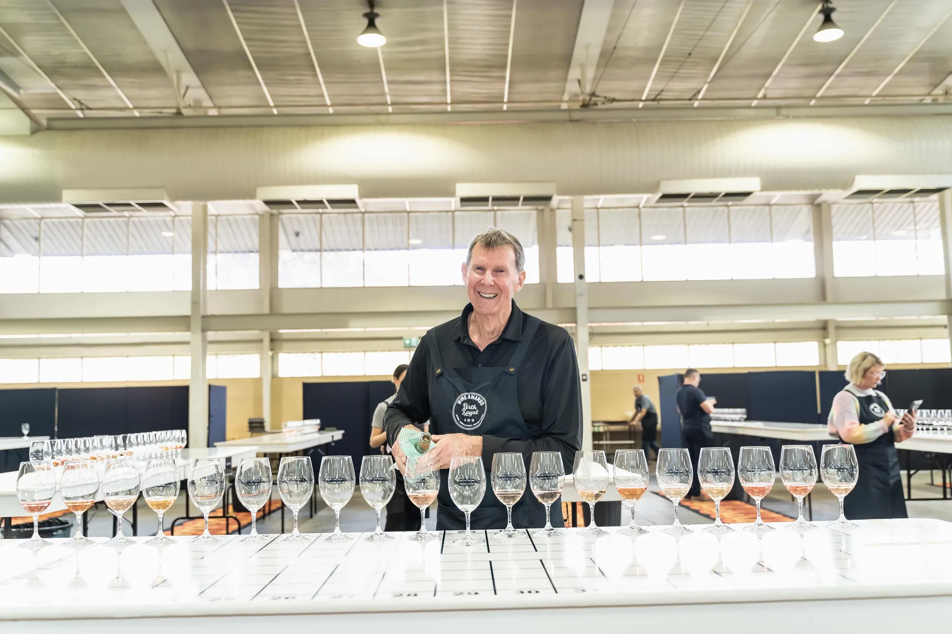 Judge pouring wine into a row of tasting glasses during judging at the Perth Royal Food Awards.