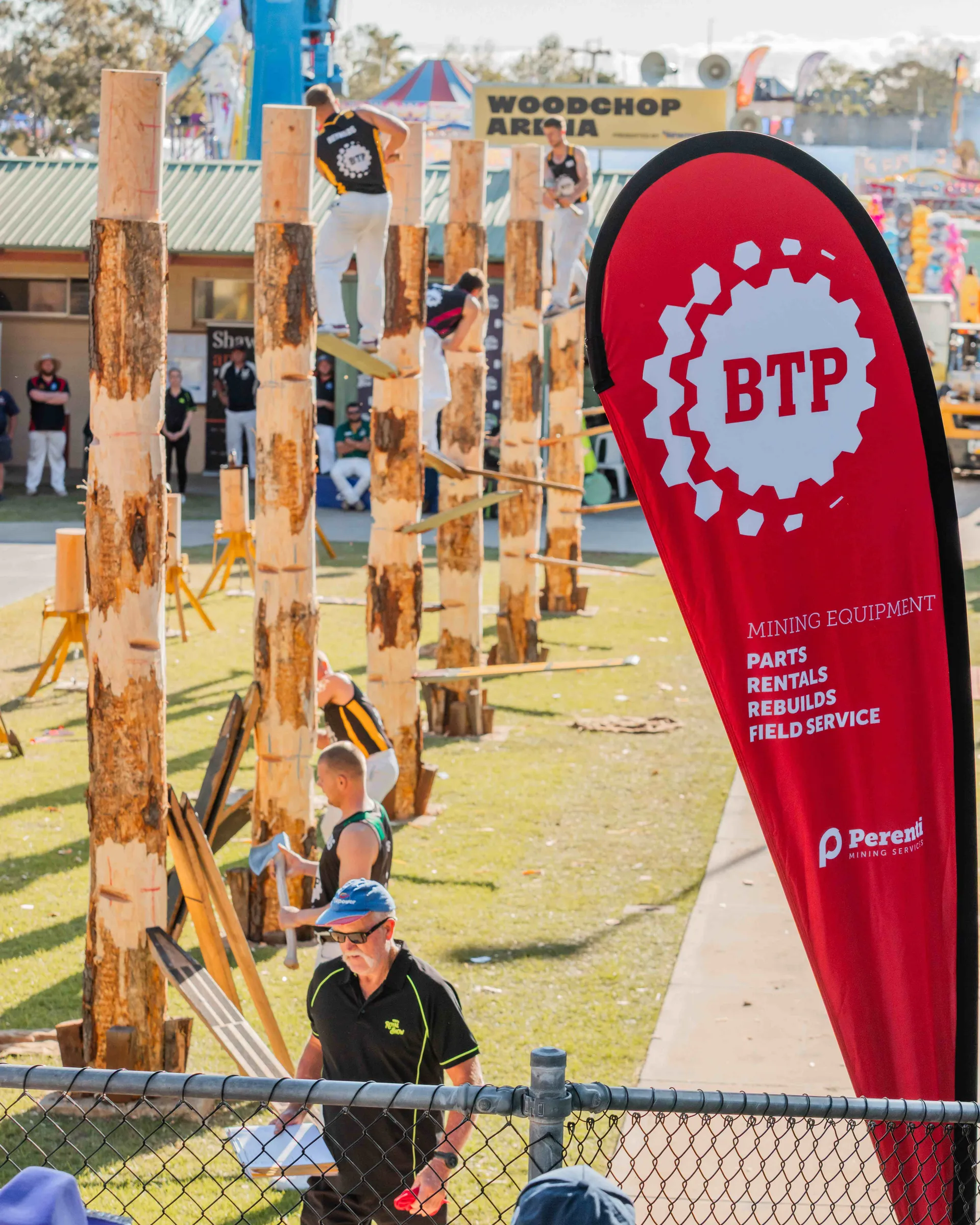 Competitors taking part in a woodchopping event at the Perth Royal Show, with spectators watching the action in the arena.