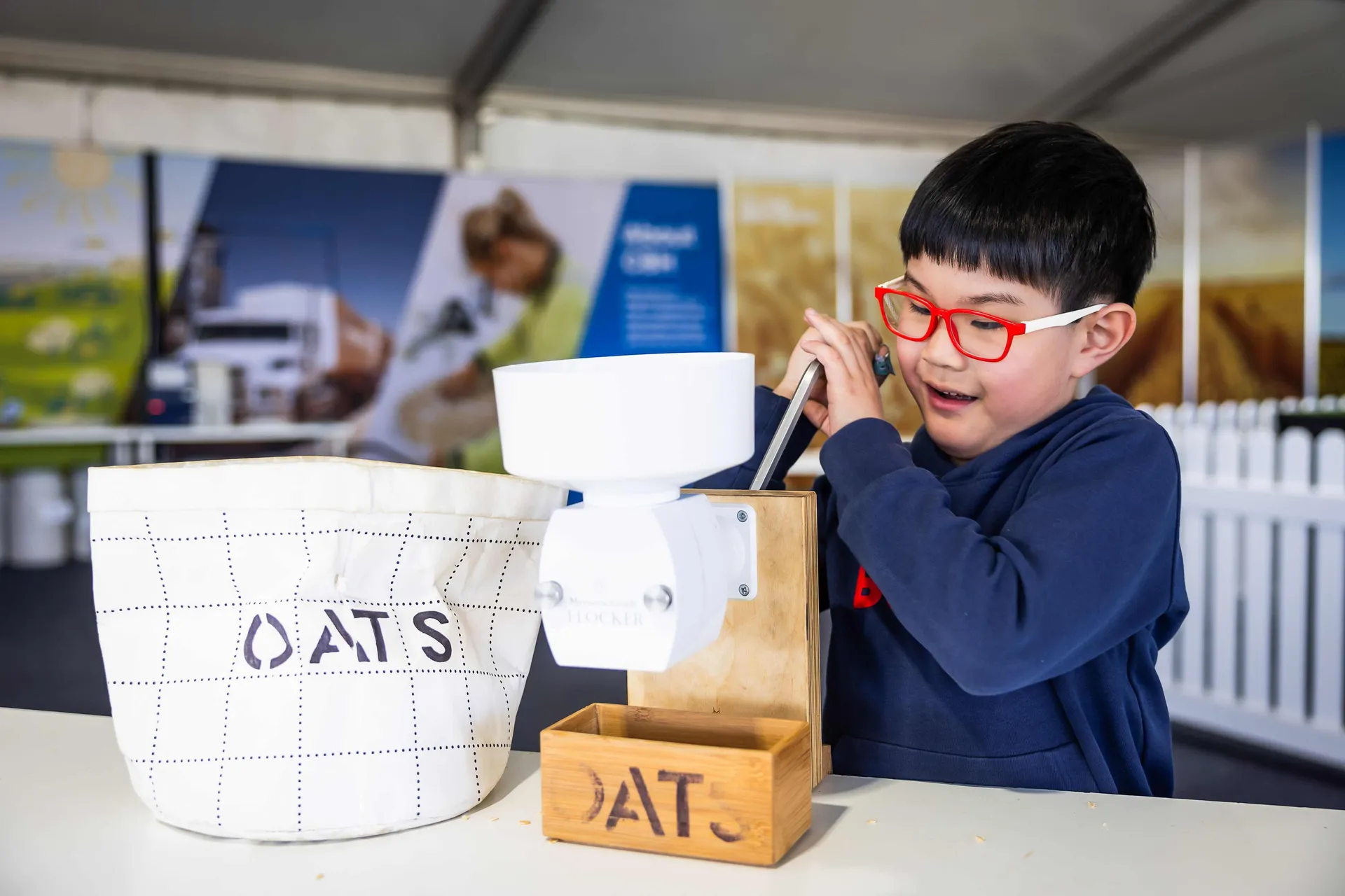 Child using a grain mill at an agricultural display.
