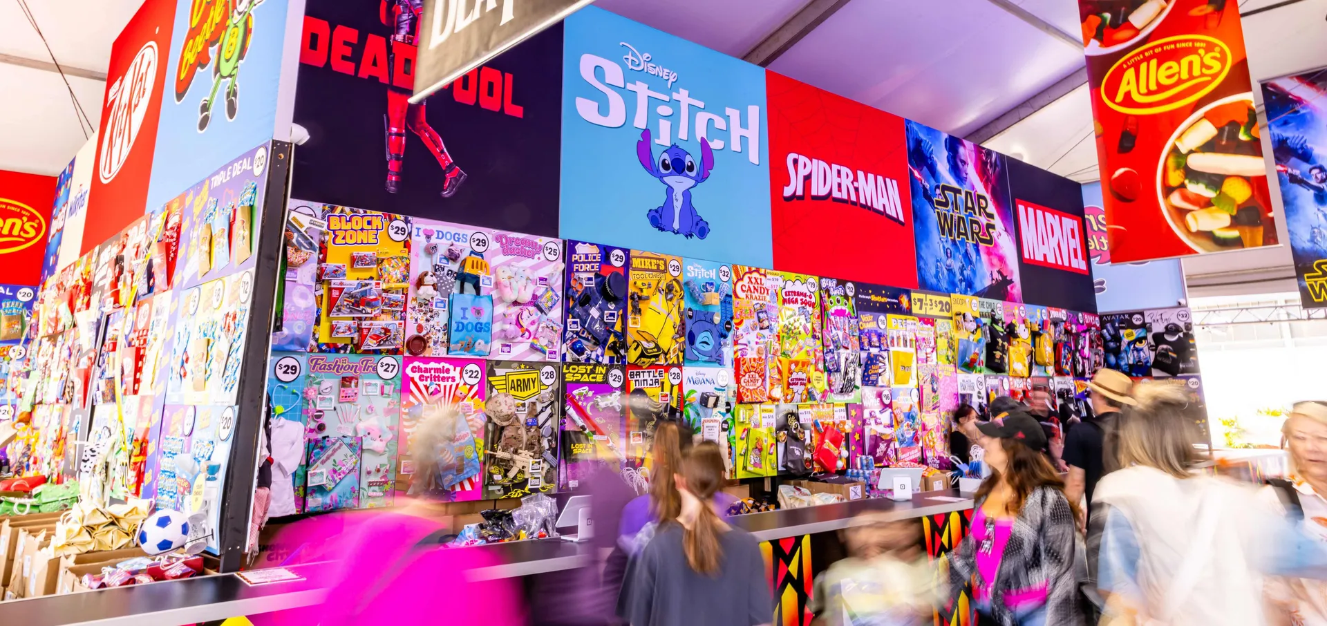 Busy showbag pavilion at the Perth Royal Show with colourful displays of themed showbags and crowds browsing stalls.