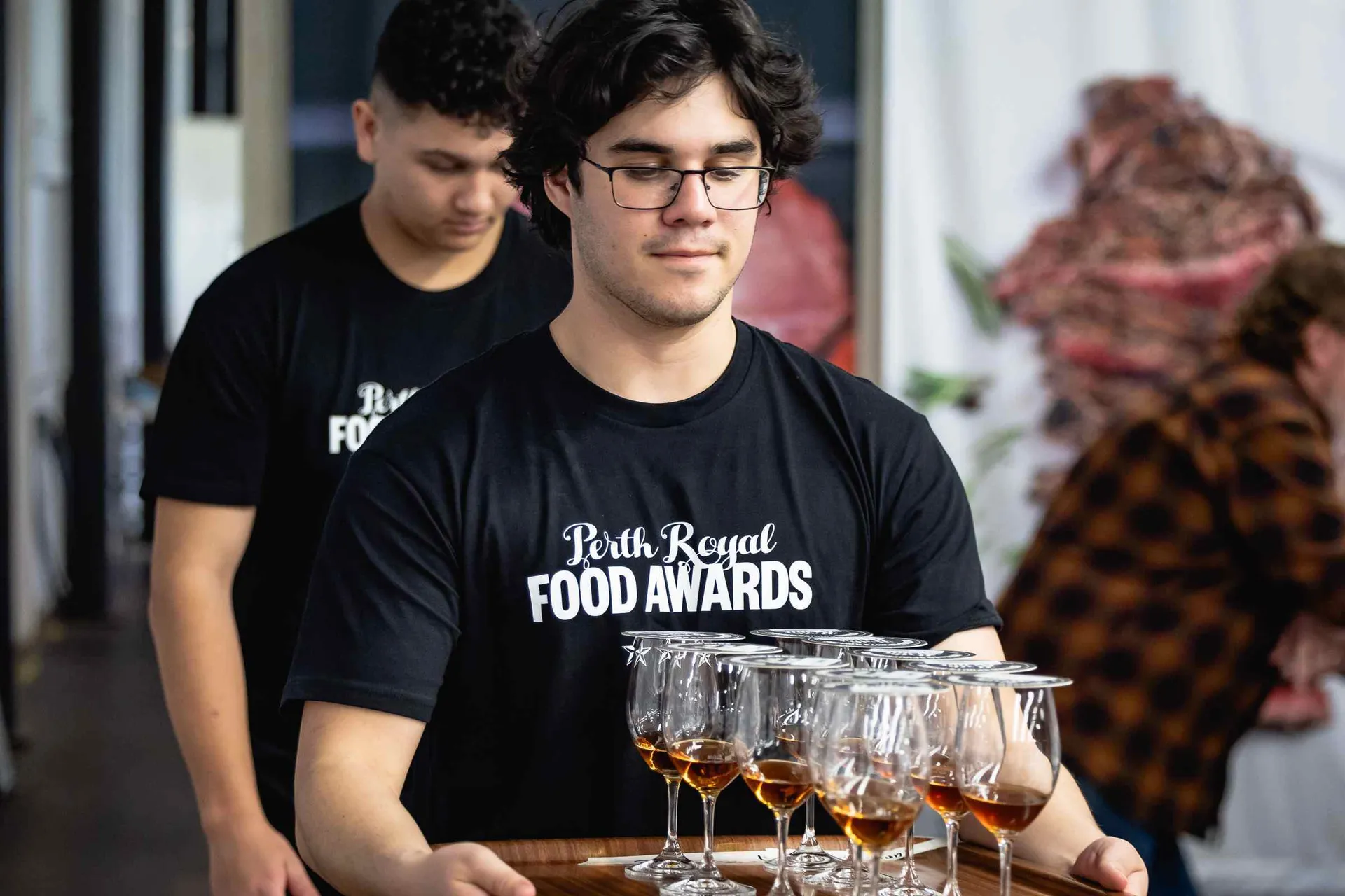 Staff carrying drink samples for judging at the Perth Royal Food Awards.