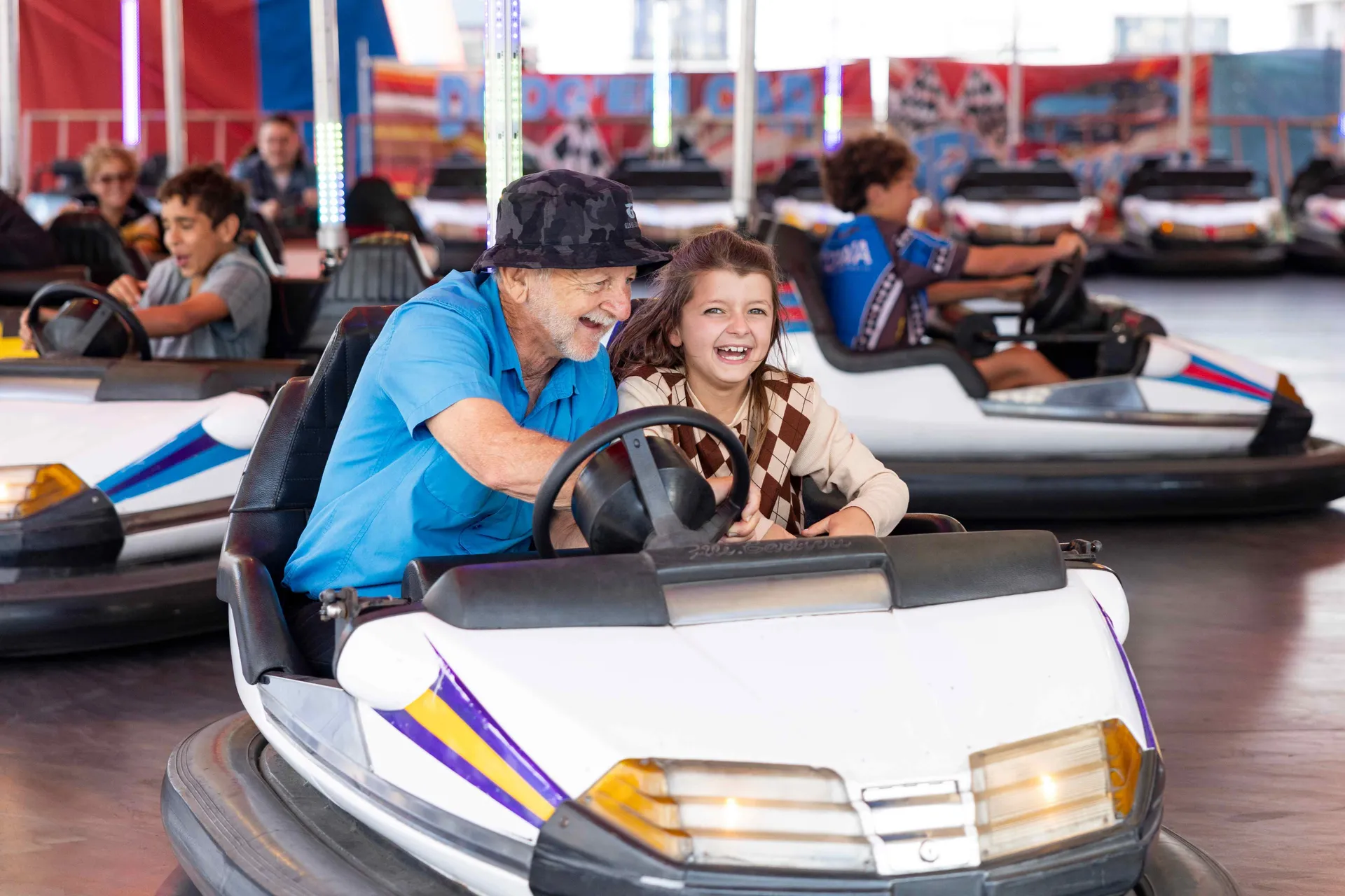 Older man and young girl laughing together while riding dodgem cars at the Perth Royal Show amusement rides.