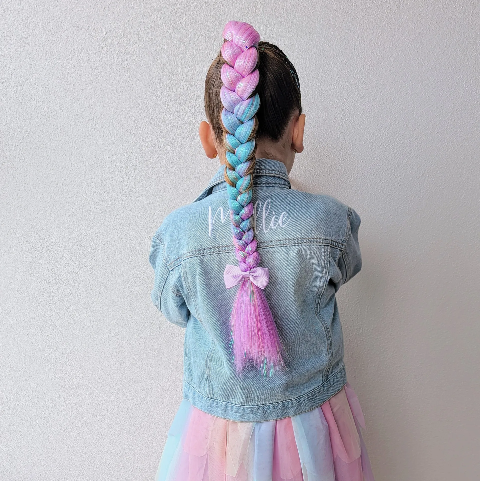 child with extensions of blue and pink plaited hair 