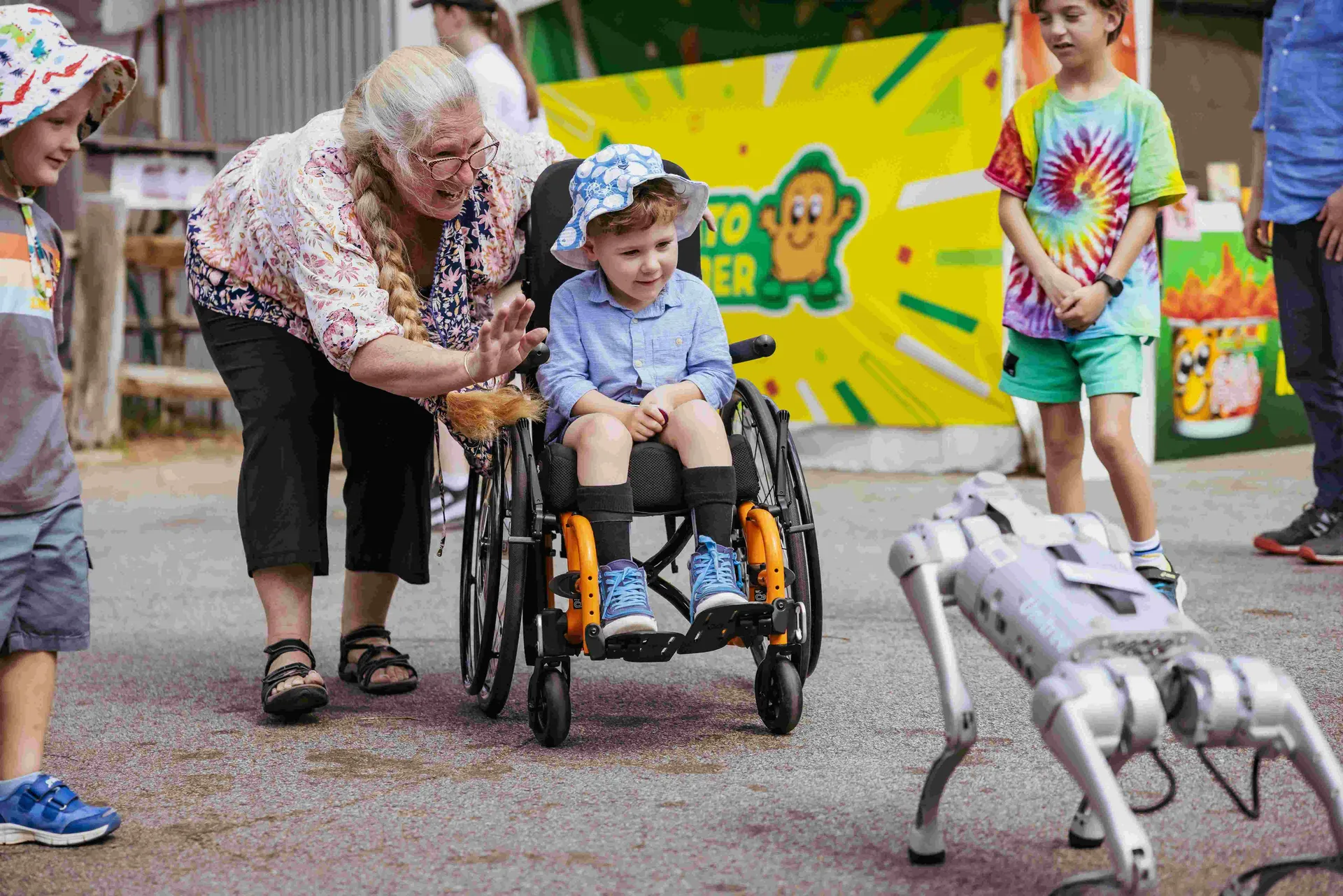 Child in a wheelchair interacting with a robotic dog at Claremont Showground.