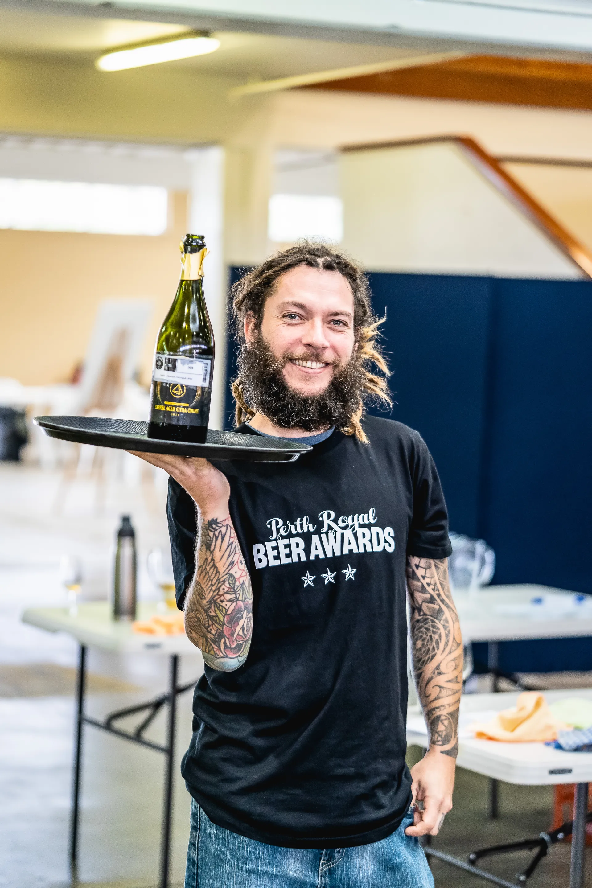 Staff member holding a beer bottle on a tray at the Perth Royal Beer Awards